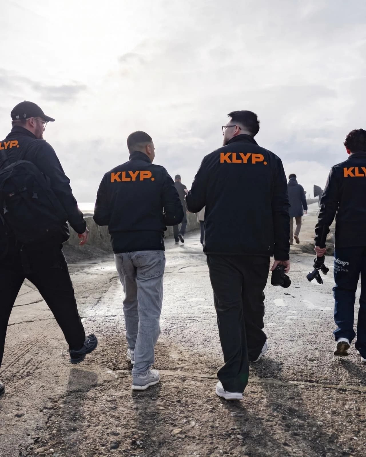 L'équipe Klyp en veste floquée marchant vers un lieu de tournage en bord de mer